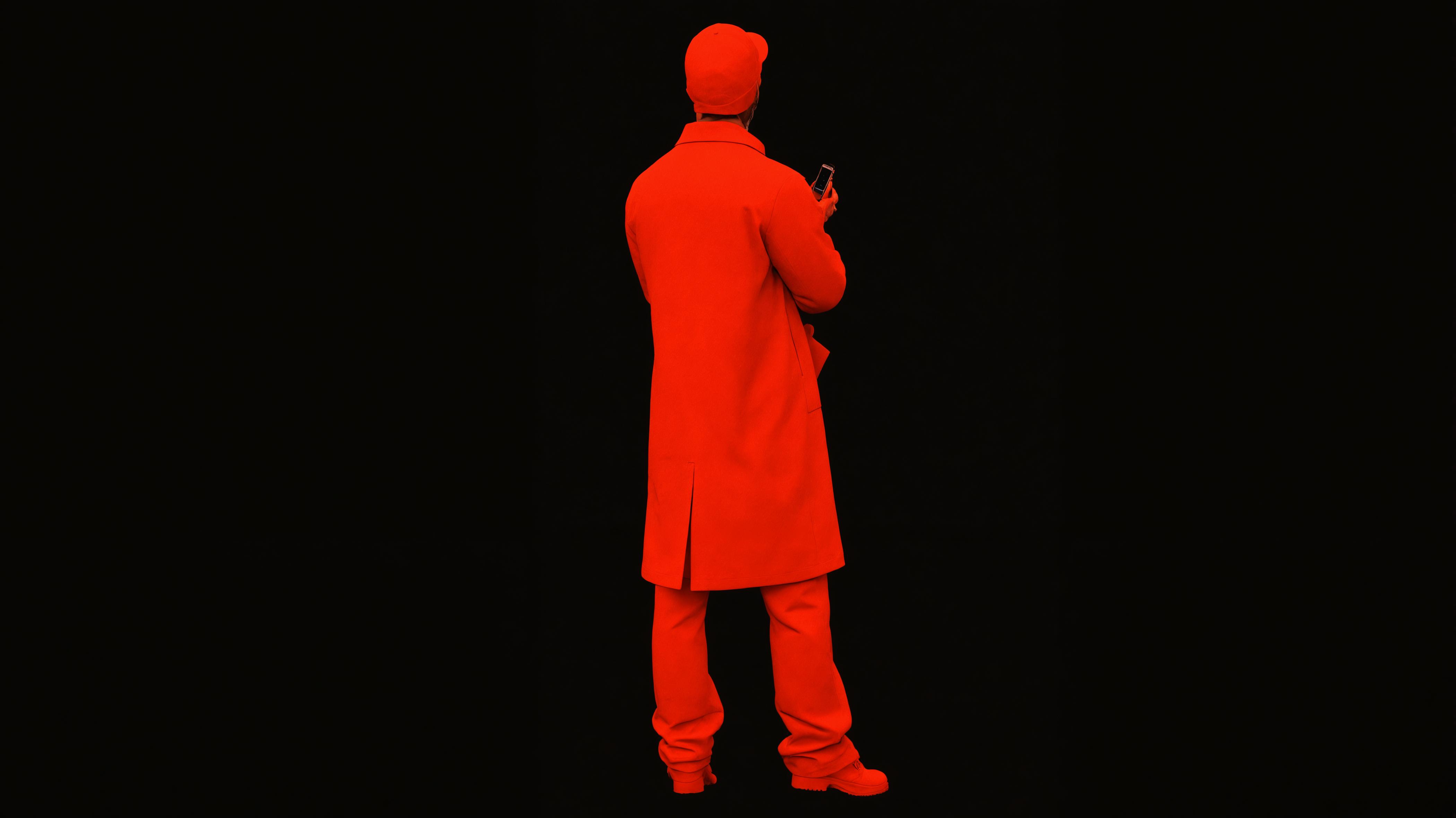 In the image, a person is captured from behind, clad entirely in a vivid red ensemble, with a striking contrast against the black background. The individual is holding a smartphone, suggesting a modern, tech-savvy context. This striking visual is a result of the 'Enhance' tool, which is known for its ability to upscale images with a creative twist, adding a bold and vivid twist to the original photo.