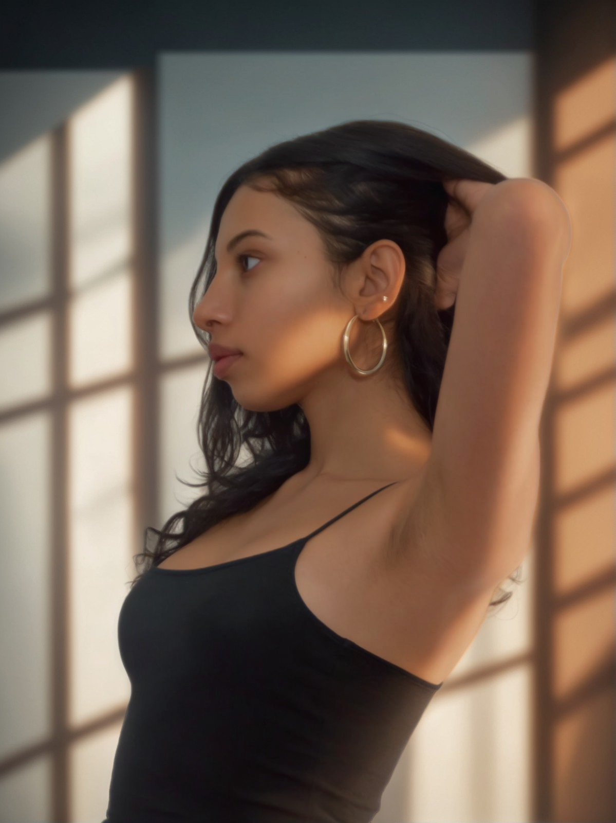 In this image, a young woman with dark hair and large hoop earrings stands against a backdrop of a room with a grid-patterned window, casting an array of soft shadows. The lighting creates a warm and serene atmosphere, highlighting the woman's features and the texture of her black tank top. The 'Replace Background' tool from Stable Assistant allows users to seamlessly change the setting behind a subject, demonstrating its versatility and ease of use in creating visually compelling images.